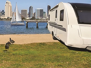 RV parked with sailboat in background