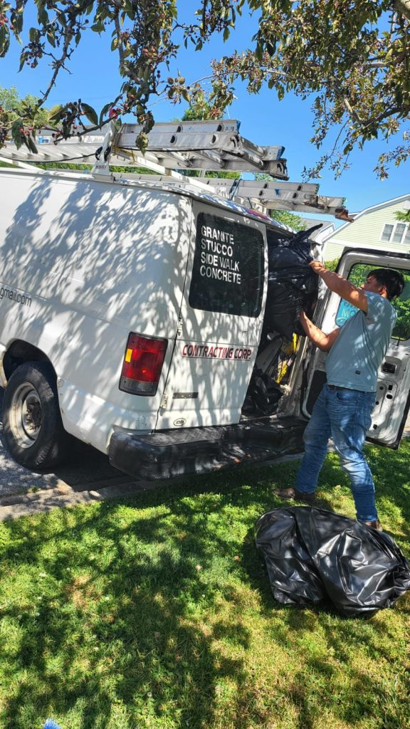 Workers in gloves separating metal scraps, cardboard, and old electronics into recycling bins at Pro Junk Dispatch facility